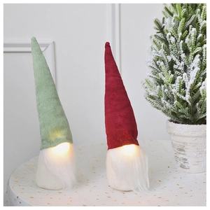 Close-up of glowing Christmas gnomes with velvet hats and long beards on a festive table