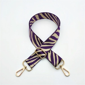 Close-up of zebra pattern handbag strap with adjustable gold buckle and swivel lobster hooks