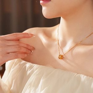 Close-up of a gold-plated cylinder pendant with sparkling zircons worn by a model
