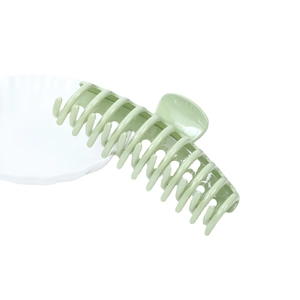 Glossy light green hair claw clip with oversized design on minimalist white background