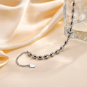 Detail view of silver oval bead chain jewelry with K18 engraved tag on satin background