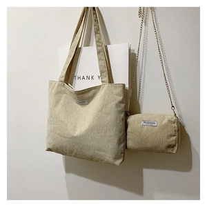Detail view of beige corduroy tote bag set with matching small chain pouch on white wall