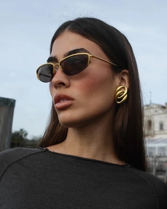 Close-up of a model wearing twisted double oval 18K gold earrings with polished finish