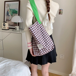 Détail du cabas en toile à carreaux avec bandoulière verte et étiquette tissée au dos