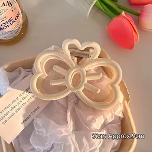 Detail of a large 9cm cream bow hair claw clip with a matte resin finish in lifestyle setting