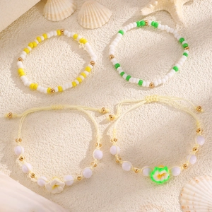 Dettaglio del set di quattro braccialetti da spiaggia con fiori di frangipane e perline