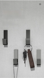 Minimalist black adhesive hooks mounted on wall holding car keys and leather strap
