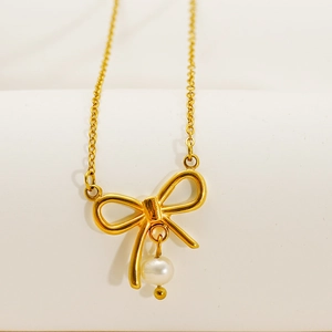Collier chic plaqué or 18k avec pendentif nœud et perle ronde blanche sur fond blanc pur