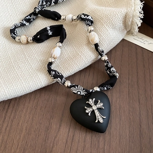 Close-up of heart pendant necklace with gothic cross and leopard print fabric chain