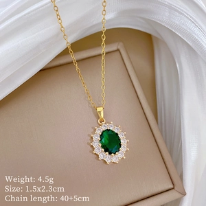 Detail shot of a gold necklace with an emerald pendant and pavé crystals on a jewelry box