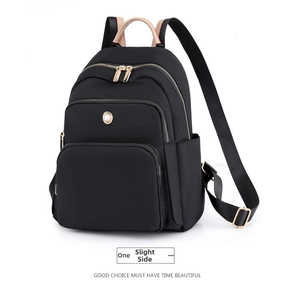 Dettaglio dello zaino in nylon nero con zip dorate e manico in pelle beige