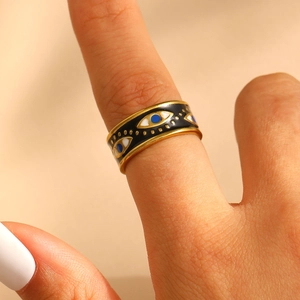 Detail of gold evil eye ring with blue and black enamel worn on the index finger