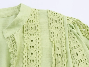 Detail of light green crepe fabric with hollow lace embroidery and geometric patterns