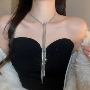 Dettaglio di una collana a Y argento con strass scintillanti indossata da una modella