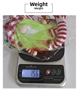 Close-up of a Christmas gnome doll with green beard weighing 156g on a digital scale