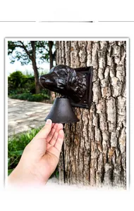 Detail of vintage cast iron dog head doorbell mounted on tree trunk in garden