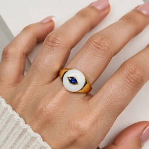 Macro view of gold ring with evil eye blue stone worn on hand by model