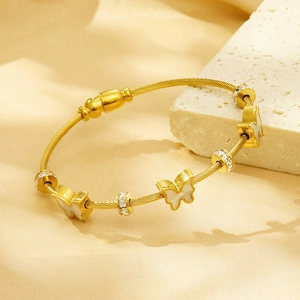 Close-up of golden butterfly bracelet with twisted chain on white textured stone