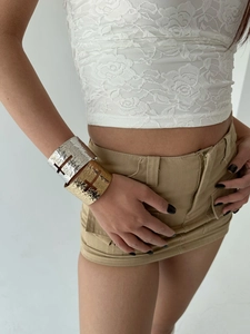 Detail of gold and silver hammered metal bangles with geometric hollow cut-outs on wrist