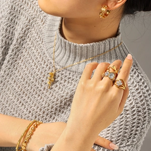 Elegant gold rose jewelry set with zircon and pearls worn on a grey knit sweater