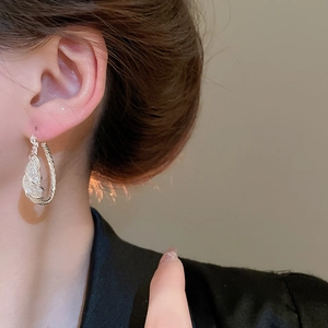 Detail of silver twisted hoop earrings with sparkling crystals worn by a model