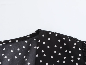 Detail view of V-neck lace patchwork on black polka dot dress with premium stitching