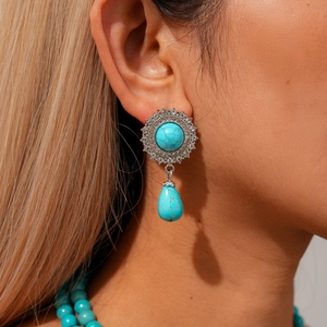 Close-up of bohemian turquoise drop earrings with vintage silver floral engraving details