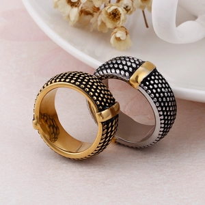 Detail of vintage wide stainless steel rings with gold dotted texture leaning on a cup