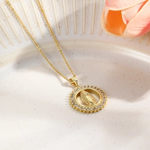 Golden copper necklace with Virgin Mary pendant and cubic zirconia in a ceramic dish