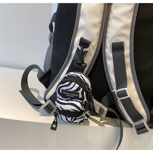 Detailed close-up of zebra pattern mini bag charm with black zippers and clip