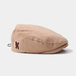 Close-up of beige corduroy kids hat featuring a brown letter K embroidery and textured fabric