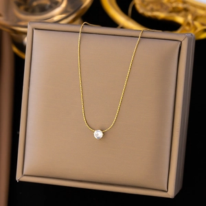 Nahaufnahme einer goldenen Halskette mit rundem Zirkonia-Anhänger in einer Geschenkbox