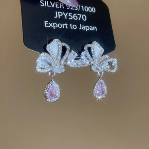 Macro shot of silver bow earrings featuring pink teardrop zircons and S925 engraving
