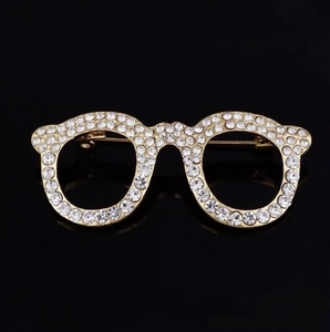 Close-up of gold glasses brooch with pavé set crystals and metal pin clasp