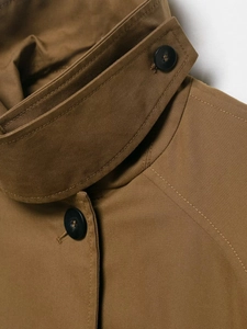 Detail of a brown trench coat collar showing diagonal twill texture and black button