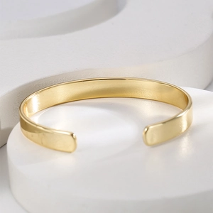 Detailed view of gold plated brass open cuff bracelet with polished metallic finish