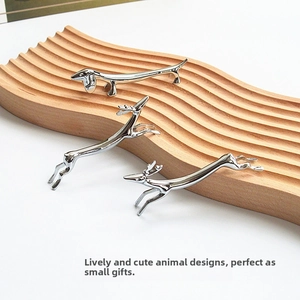 Detail of silver Dachshund and Deer shaped metal chopstick rests on wooden stand