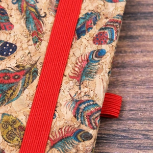 A5 cork cover notebook with colorful feather print and a red elastic band closure