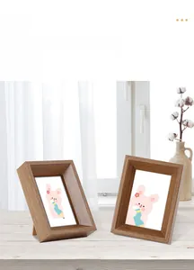 Close-up of a minimalist deep brown wooden photo frame on a desktop with cotton flowers