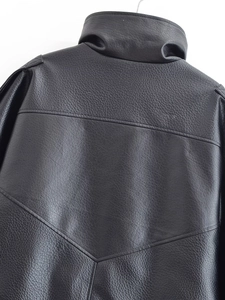 Détail du col montant et des coutures d'épaule sur veste en simili cuir noir grainé