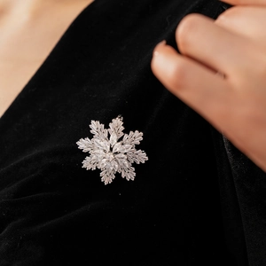 Macro detail of silver snowflake brooch with sparkling cubic zirconia on black velvet