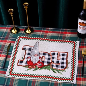 Detailed view of woven Christmas gnome placemat with JOY text on festive holiday table