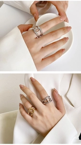 Detail of 18K gold plated and silver chain link rings on a hand holding a ceramic cup