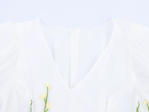 Détail du dos d'une robe blanche avec fermeture éclair invisible et broderies florales