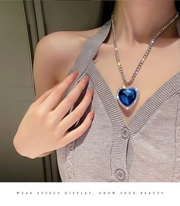 Nahaufnahme einer blauen Herz-Halskette mit funkelnden Kristallen an einem Model