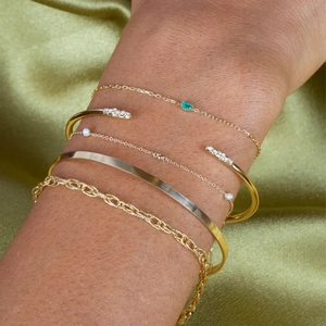 Macro view of five-piece gold bracelet set with emerald green zircon and small pearls