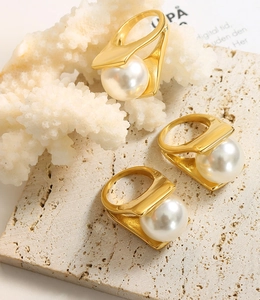 Detailed view of three 18k gold plated titanium rings with large white pearls on stone