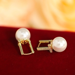 Detail of elegant gold tassel earrings with round white pearls on a velvet base