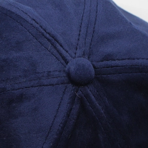 Macro shot of dark blue velvet baseball cap showing 6-panel stitching and top button detail