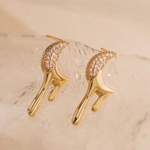 Detail shot of gold-plated celestial stud earrings with sparkling zircon on ice texture